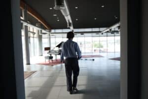 Hombre caminando hacia el piano en una luminosa sala de eventos en Madrid.